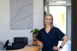 © Wavebreak Media - Smiling woman in scrubs standing at reception desk in medical clinic, copy space