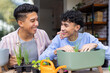 © Wavebreak Media - Smiling gay couple planting herbs together in pots at home, enjoying gardening