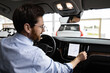 © sofiko14 - Professional setting demonstrates modern technology in automobiles, focusing on user experience and innovation. Businessman sits inside vehicle in dealership, interacting with car's navigation system.