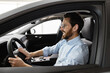 © sofiko14 - Businessman sits inside car at dealership, smiling and checking vehicle controls. Confident and successful buyer looking forward to new purchase.