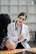 © Satori Studio - Female doctor in white coat consulting with a patient in a modern medical office, discussing health and providing professional advice.