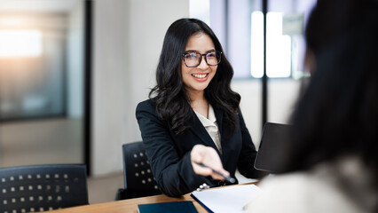 Two businesswoman working together on digital tablet. Creative female executives meeting in an office using tablet pc and smiling.