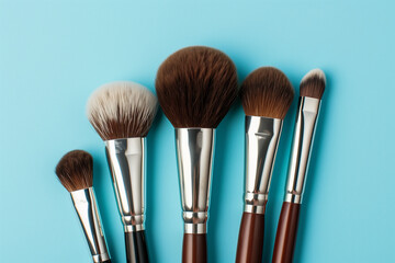 Wall Mural - row of makeup brushes are displayed on a blue background. The brushes are of different sizes and colors, and they are arranged in a neat row. Concept of organization and attention to detail