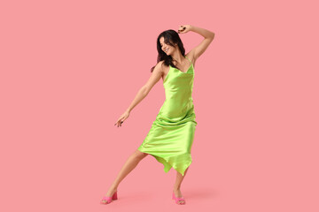 Sticker - Beautiful young woman in stylish green dress dancing on pink background