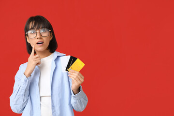 Poster - Beautiful young woman with credit cards on red background