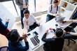 © alfa27 - Top view of multiracial creative business men in white and black formal clothes disputing at a meeting using gadgets during the conference while sitting at the modern office.