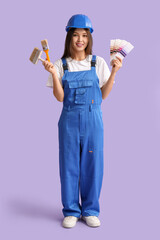 Wall Mural - young female painter with brushes and color swatches on lilac background