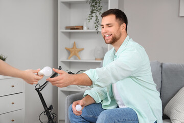 Wall Mural - Young man taking light bulb from woman at home