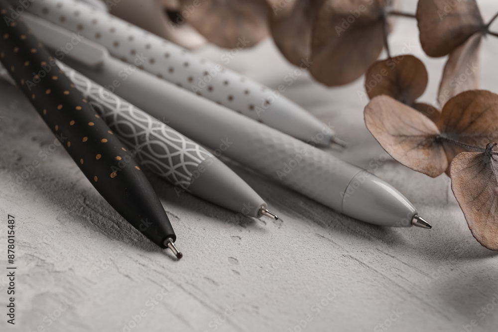 Beautiful eucalyptus branch and pens on grey grunge background, closeup
