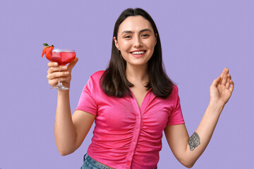 Poster - Beautiful young woman holding glass of tasty cocktail with strawberry on lilac background