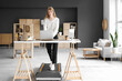 © Pixel-Shot - Young businesswoman on treadmill working with laptop at table in office