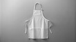 © Wanlop - Clean white apron mock-up isolated on soft gray background, empty, crisp, and ironed, with a slight fold at the bottom.