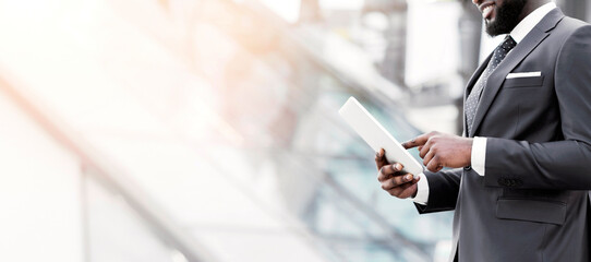 Wall Mural - Black Business Guy Browsing On Digital Tablet Walking In Urban Area. Cropped, Empty Space