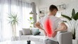 © Stocks Buddy - A young man with back pain holds the lower half of his body in the living room at home healthcare and back pain