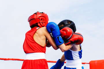 Two young boxers in protective gear spar in a boxing ring