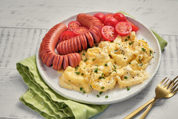 Canvas Print - A plate of scrambled eggs with sausage and tomatoes on top