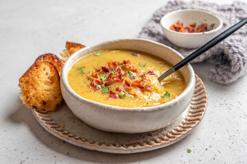 Wall Mural - A bowl of soup with bacon and parsley on top sits on a white plate