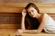 © SHOTPRIME STUDIO - Relaxing in the sauna woman in towel resting on wooden floor next to sauna bench