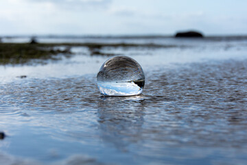 Beach and sea reflected in a sphere lying  in the water