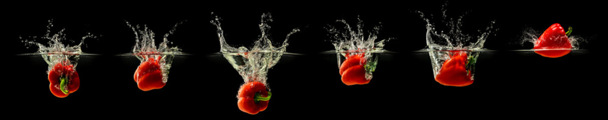 Wall Mural - Group of bell pepper falling in water with splash on black background