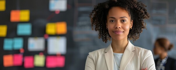 Wall Mural - A woman with curly hair is standing in front of a board with colorful sticky notes. She is wearing a white jacket and smiling