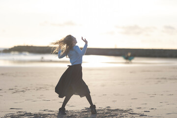 Wall Mural - A woman is dancing on the beach in a black skirt