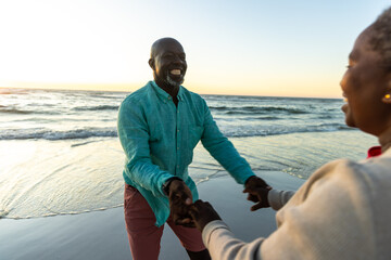 Senior African American couple enjoys a playful moment on the beach, with copy space