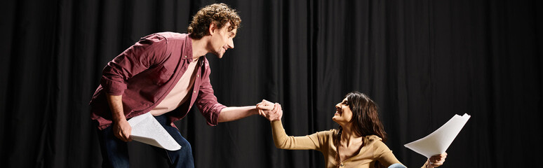 Wall Mural - Handsome man and woman rehearse lines on stage, holding scripts.