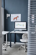 © Seventyfour - Vertical still life shot of modern veterinarian workplace with dogs main body proportions poster on blue wall and computer displaying veterinary clinic appointment, copy space