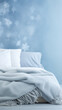 © jamalnasro - A cozy blue blanket and white pillows on a bed with a snowflake pattern on the wall, perfect for winter and holiday designs.