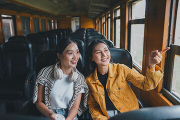 Two friends savor the sights on their train ride, sharing a moment of joy as they travel to a new destination