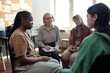 © pressmaster - Young African American woman, mature female psychologist and blond girl looking at brunette patient in green pullover telling her story