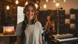 © Alex - Smiling female musician with headphones standing in a recording studio. Studio portrait with blurred background. Music production and creativity concept for design and print.