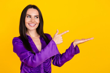 Wall Mural - Photo of positive smiling lady promoter hold hand look pointing empty space isolated yellow color background