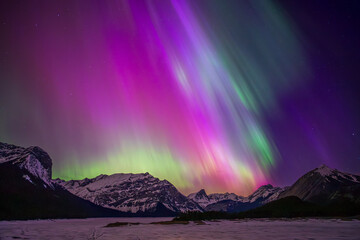 aurora borealis painting the sky purple and green over snowy mountains