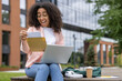 © Liubomir - Happy student receives letter of approval sitting on university campus bench with laptop. Joyful reaction to good exam results or enrollment confirmation while studying outdoors.