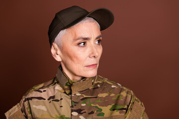 Poster - Photo of attractive confident elderly lady dressed camo uniform looking empty space isolated brown color background