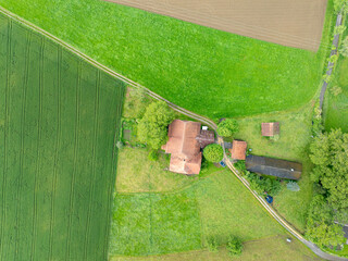 Wall Mural - Aerial view farm house buildings in rural area in Switzerland. Buildings in the middle of agricultural fields.