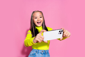 Wall Mural - Photo of good mood adorable girl with dyed hairdo dressed yellow shirt recording video on smartphone isolated on pink color background