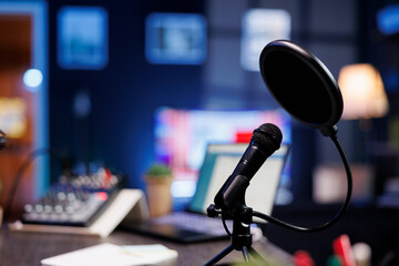 Leinwandbilder - Closeup of a professional podcast microphone resting on a desk in a recording ready podcasting home studio. Selective focus of podcast equipment in empty room, ready to be used for online streaming