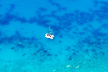 Beautiful blue clear sea and a sailing yacht as view from the air.