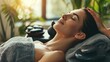 © somneuk - Serene attractive brunette woman getting hot stone massage in spa salon. Beautiful girl lying on couch enjoying body treatment in wellness center. Beauty treatment therapy, body care concept