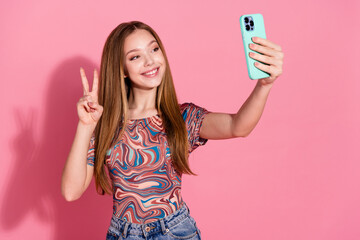 Sticker - Photo of pleasant girl with straight hair wear print t-shirt making selfie on smartphone showing v-sign isolated on pink color background