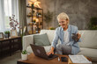 © Miljan Živković - Mature senior woman work from home on laptop and drink coffee, tea