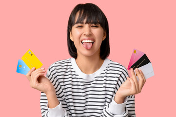 Sticker - Beautiful young woman with many credit cards showing tongue on pink background