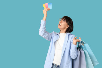 Sticker - Beautiful young woman with credit cards and shopping bags on blue background