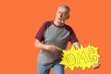 Sticker - Shocked senior man pointing at speech bubble with word OMG on orange background