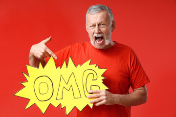 Sticker - Shocked senior man pointing at speech bubble with word OMG on red background