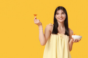 Young woman with nachos on yellow background. Cinco de Mayo celebration