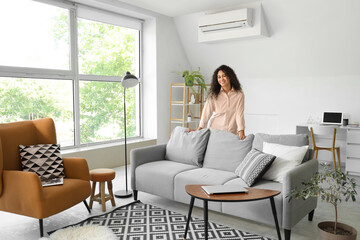 Poster - Young African-American woman behind grey sofa at home